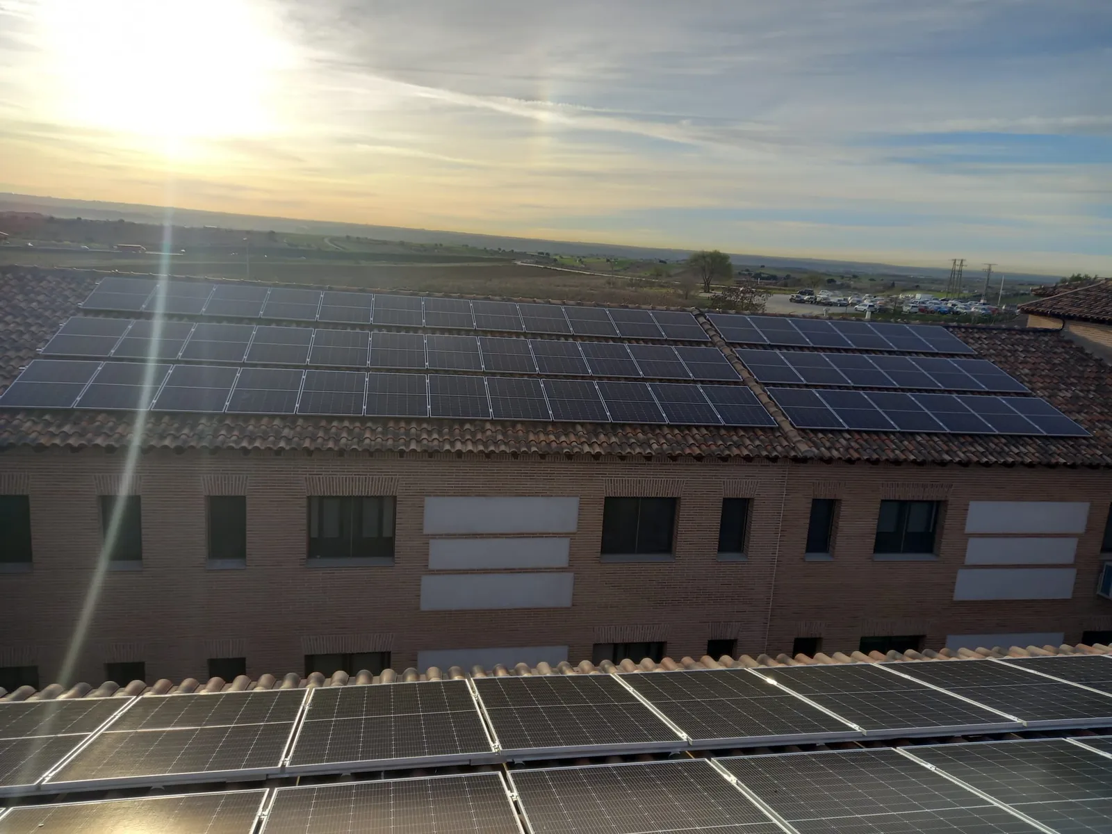 Gran instalación fotovoltaica sobre la cubierta de un edificio al atardecer