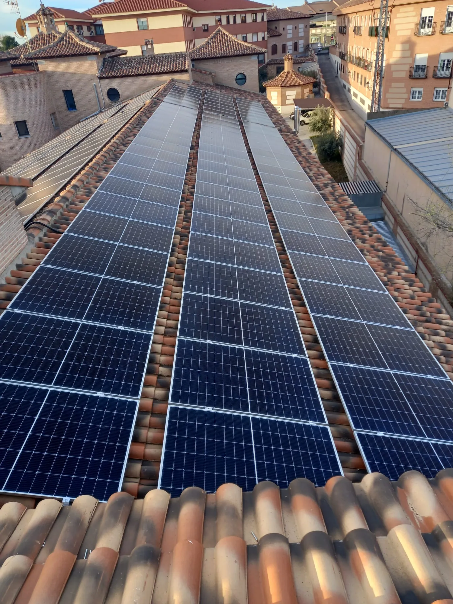 Fila de placas solares sobre tejado de teja en un edificio del centro